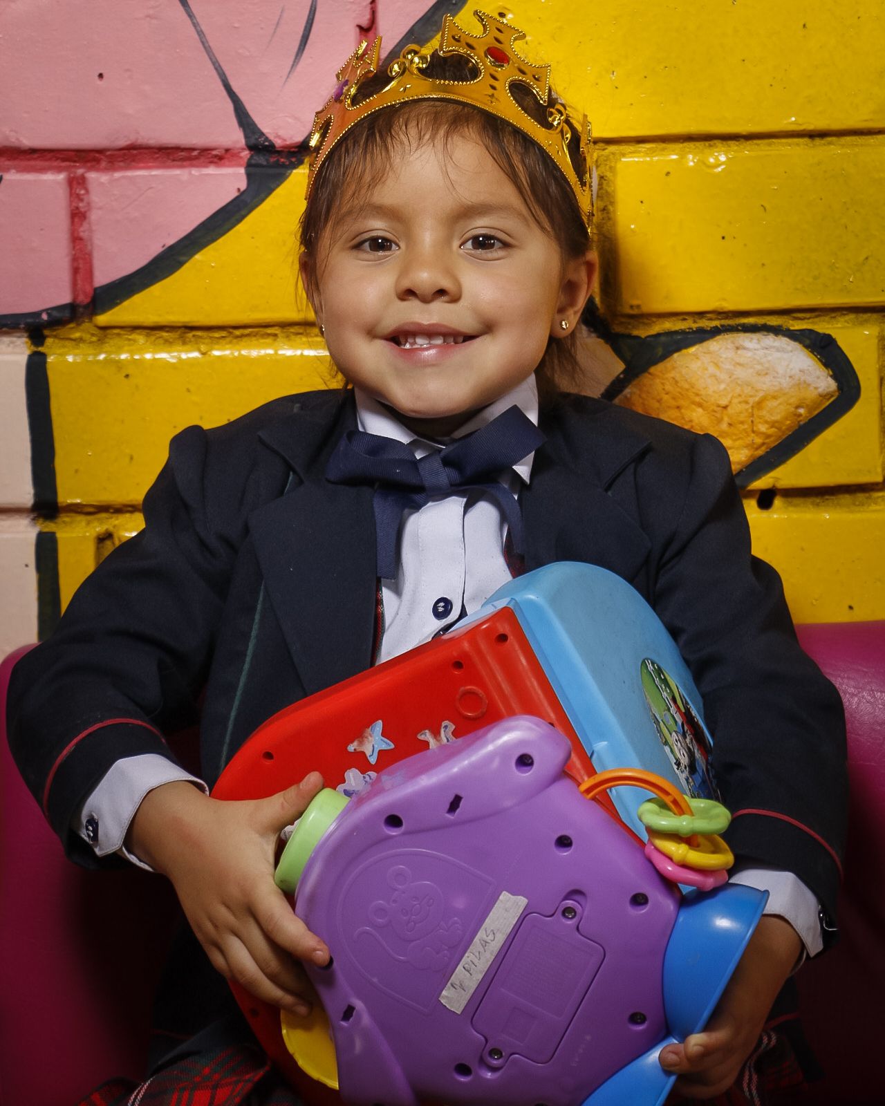 Niña de preescolar sonriendo con un juguete en las manos